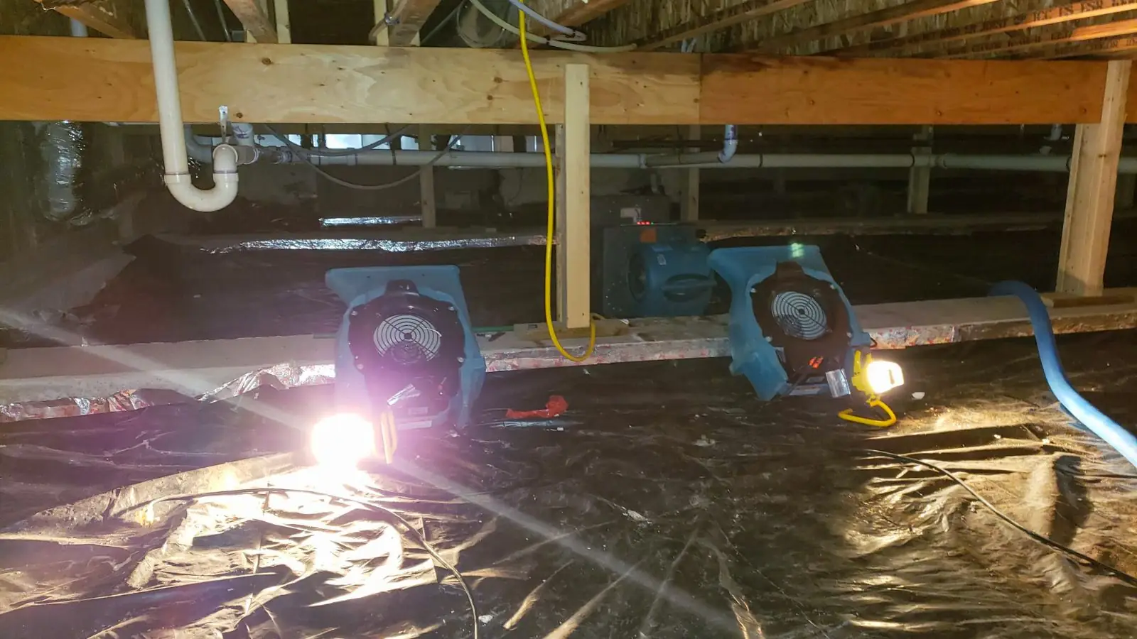 Crawl space with air movers and plastic sheeting over the ground